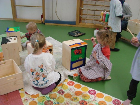 Kindergartenkinder bemalen Holzkisten mit bunten Farben