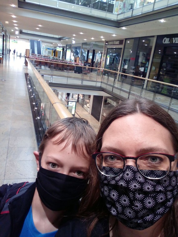 Frau und Junge mit Maske in leerem Einkaufszentrum
