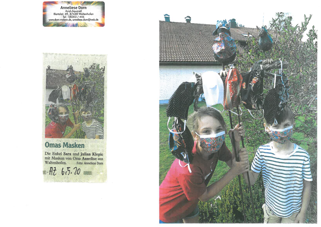 Mädchen und Junge mit bunt gemusterten Masken halten Gartenskulptur, an der viele Masken hängen