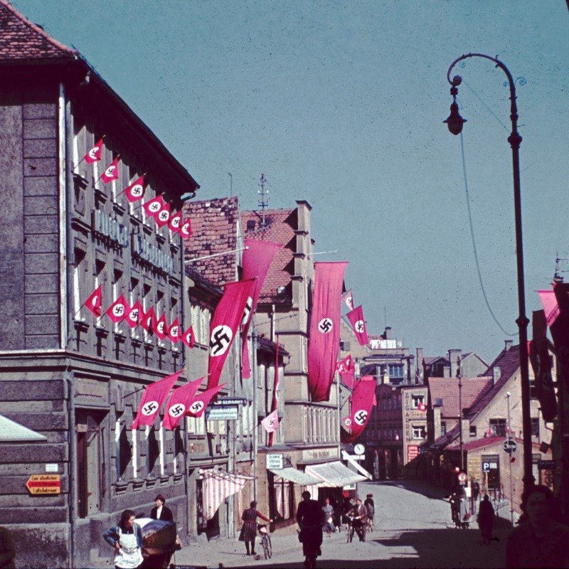 historisches Bild aus der Zeit des Nationalsozialismus: Fußgängerzone mit Hakenkreuzfahnen  