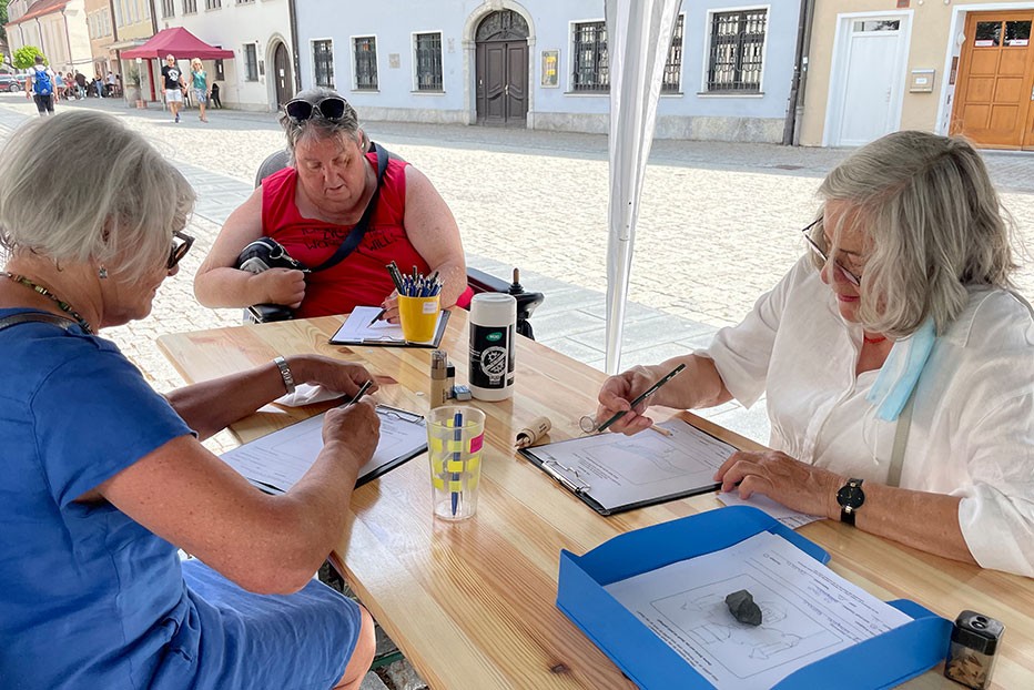Drei Frauen zeichnen an Tisch in der Altstadt Kemptens