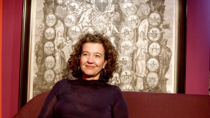 Eva Lueg vor Gemälde an Weinroter Wand