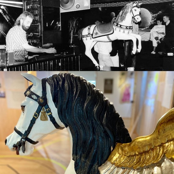 Schwarz-Weiß-Bild: Mann an DJ-Pult in Dikothek. Nebem ihm Holzfigur Pegasus und Pegasuspferd im Kempten-Museum