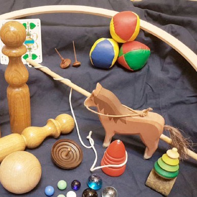 Unterscheidliche Spielsachen: Holzpferd, Jonglierbälle, Kreisel, Murmeln