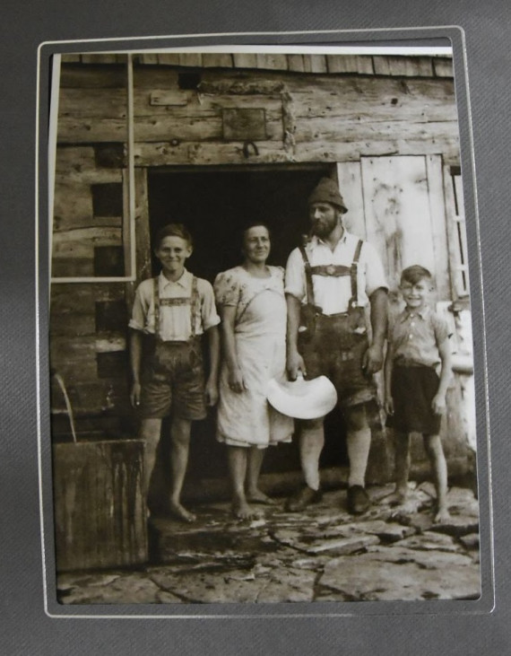 zwei Erwachsene und zwei Kinder  vor einer Käserei, die Männer in Lederhosen, historische Aufnahme 