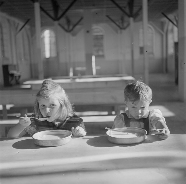 schwarz weiß Foto von zwei Kindern, die Brei essen