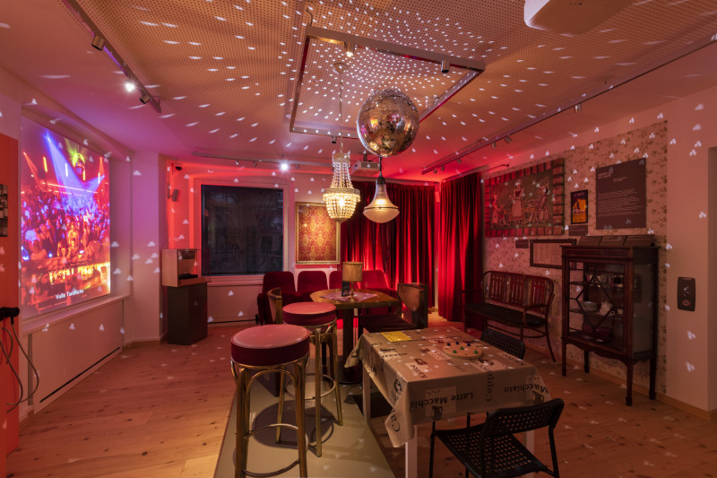 Ausstellungsraum, der wie ein Caf&eacute; eingerichtet ist mit stimmungsvollem Licht wie auf einer Tanzfl&auml;che