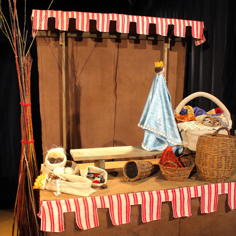 Zwei schwarz gekleidete Puppenspielerinnen mit Puppentheater